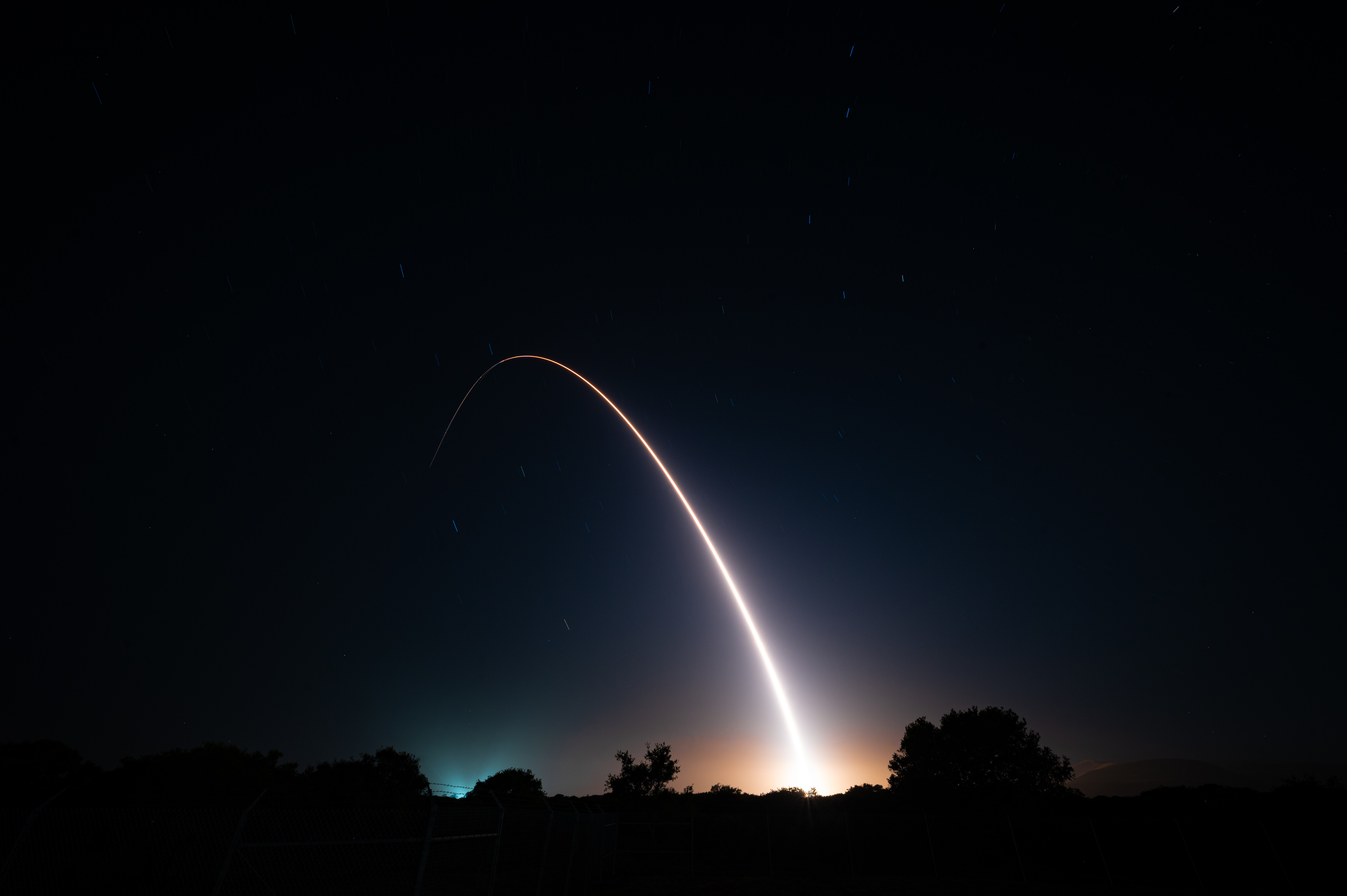 An arc of light from a missile test against a dark sky